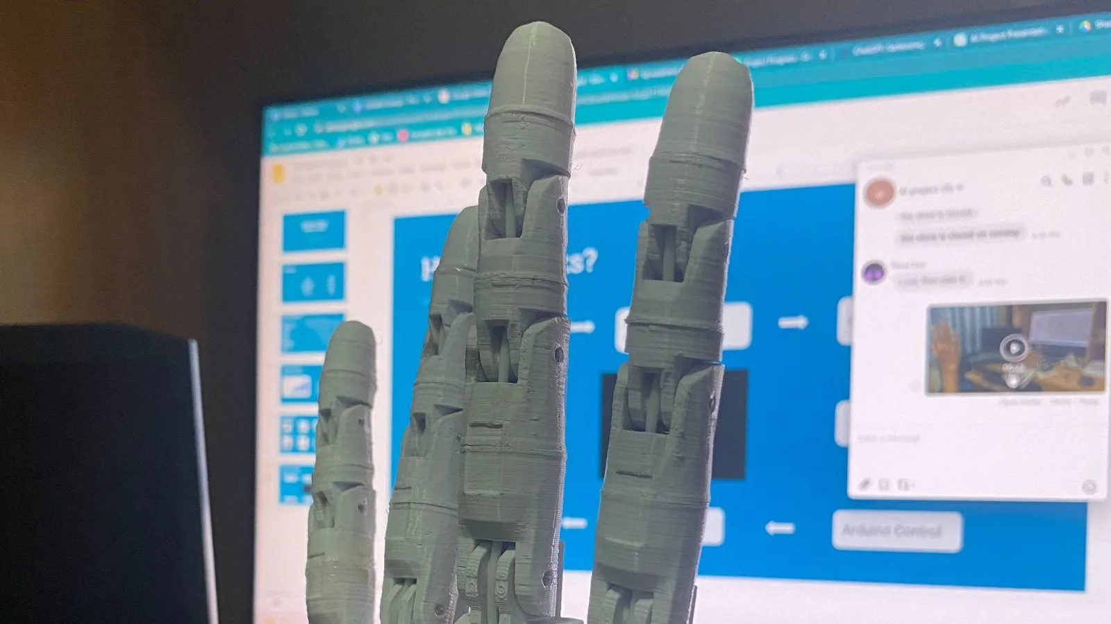 A 3D-printed robotic hand with its fingers extended, servo cables running from the wrist