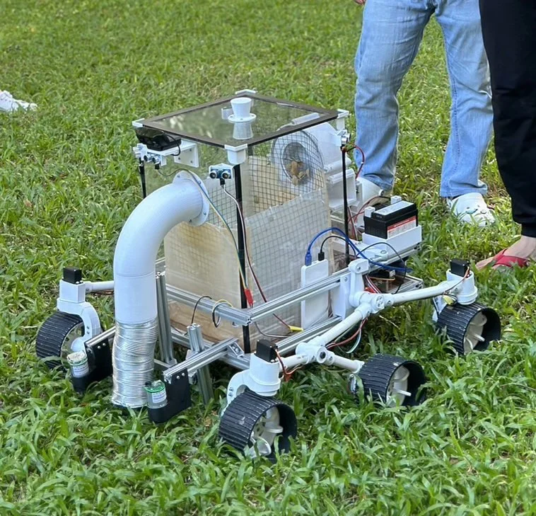 The finished robot standing on grass, showing the sealed collection box and the vacuum duct