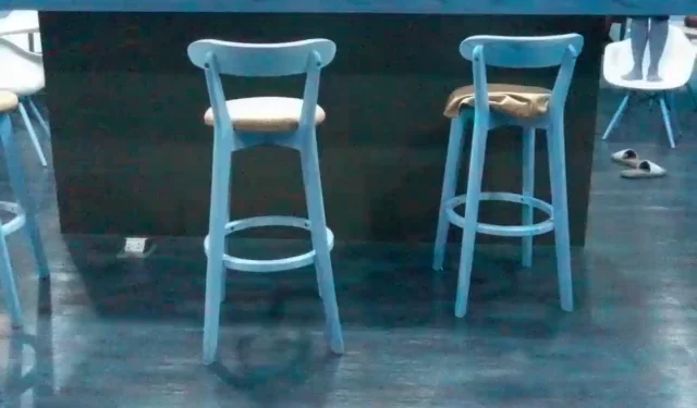 A still from the drone's camera looking across a room at two bar stools and a counter, taken from hovering height
